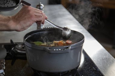 La recouvrant de légumes et en l'arrosant de bouillon à chaque fois.